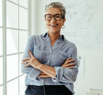 Successful senior architect standing in her office with crossed arms